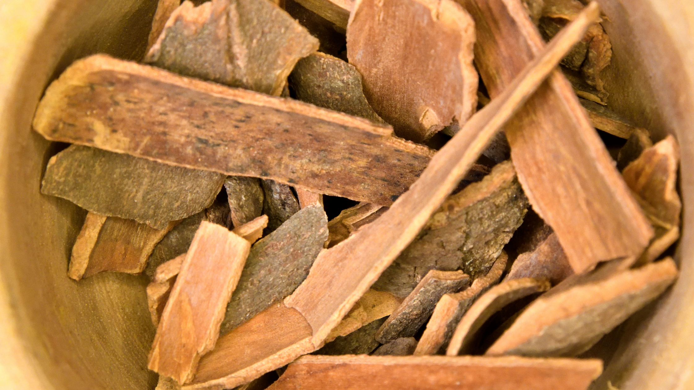 tcm herb cinnamon bark piled in a wooden bowl