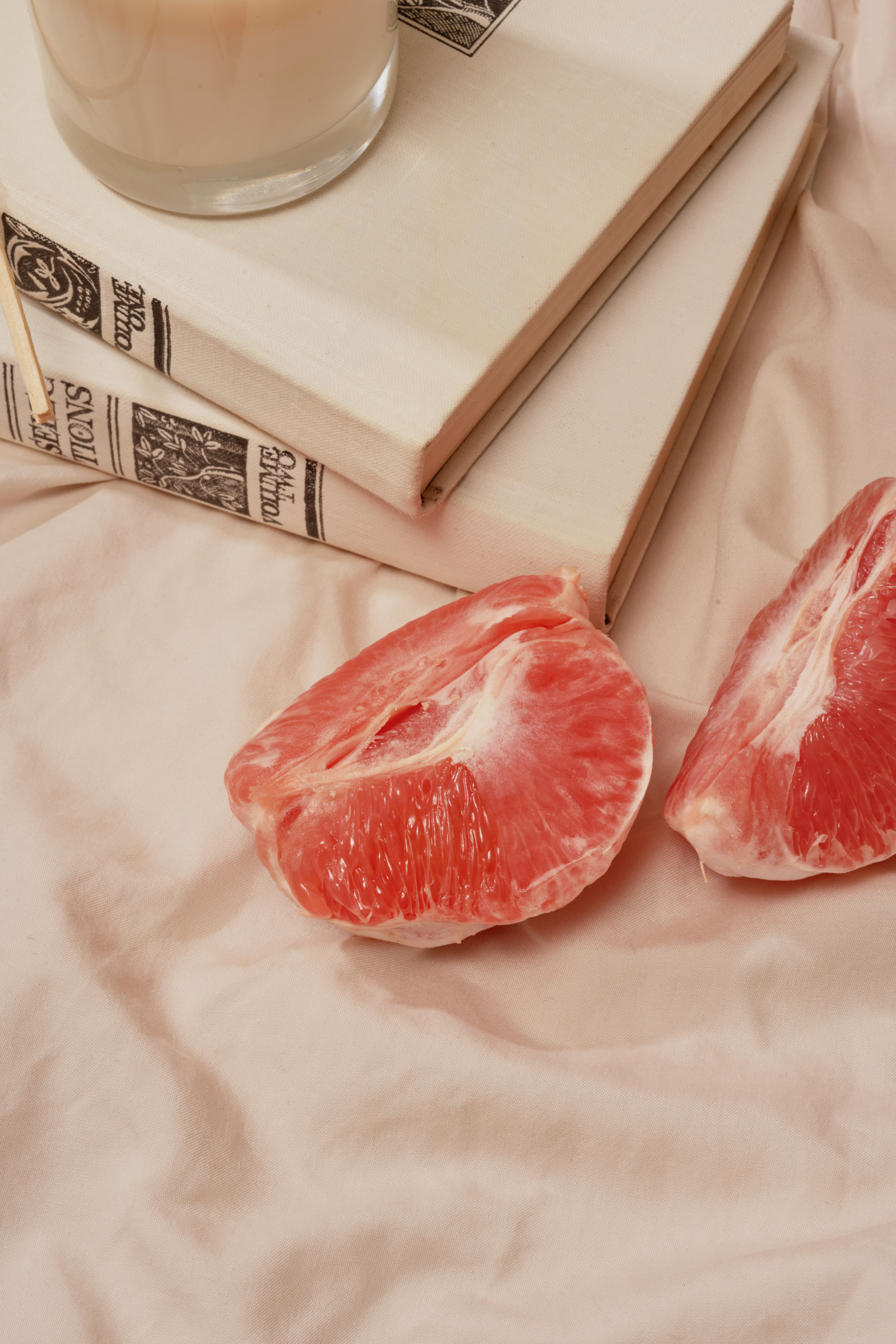 Riped grapefruit slices sits on bed sheets near books before bedtime.