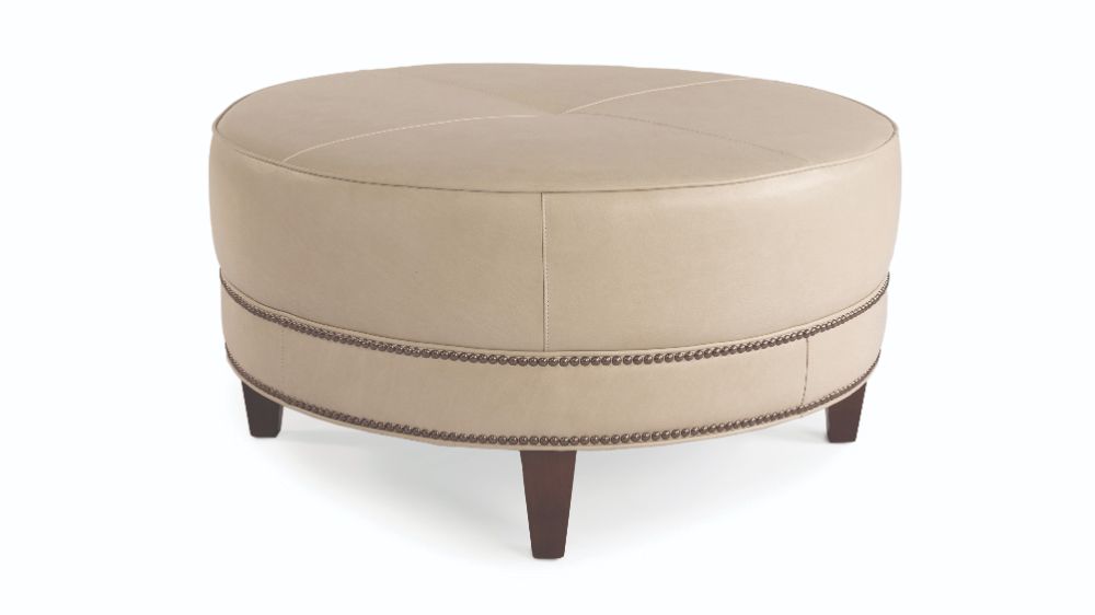A round beige leather ottoman with a wooden base that would complement a fine home.